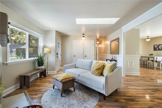 living room with dark hardwood / wood-style flooring and a skylight