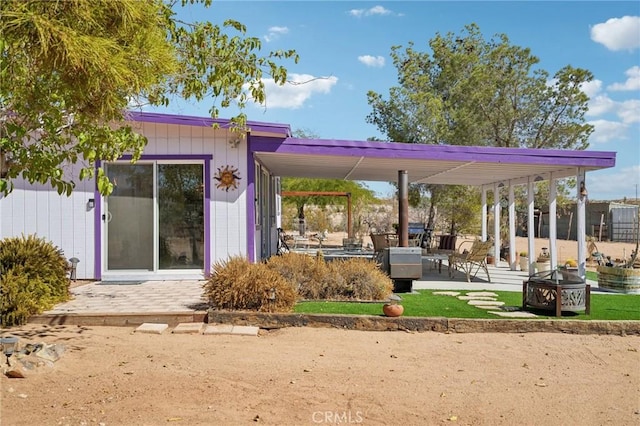 rear view of house with a pergola, a patio area, and an outdoor fire pit