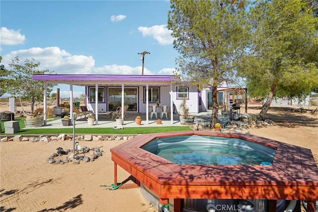 back of house featuring a patio area and an outdoor hot tub