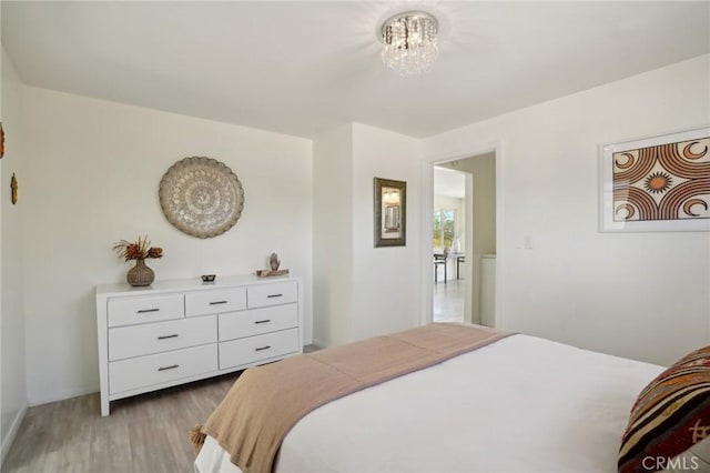 bedroom with light wood-type flooring and a notable chandelier