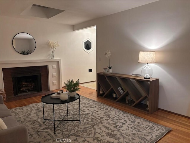 living room featuring a brick fireplace and wood-type flooring