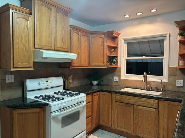 kitchen with light tile patterned flooring, white gas range, tasteful backsplash, and sink