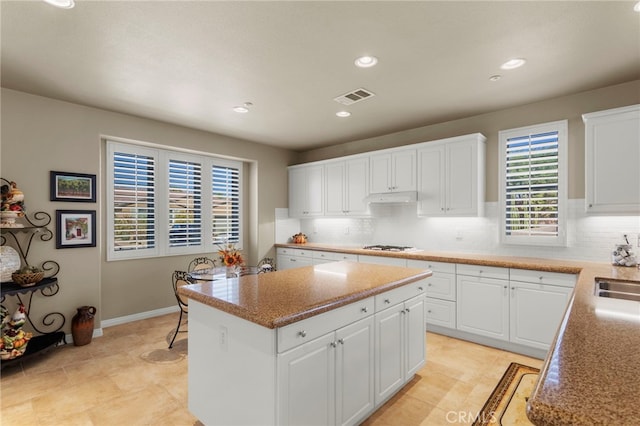 kitchen featuring white cabinets, a center island, sink, and tasteful backsplash