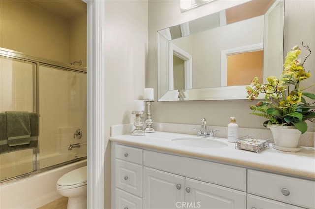 full bathroom featuring enclosed tub / shower combo, vanity, and toilet