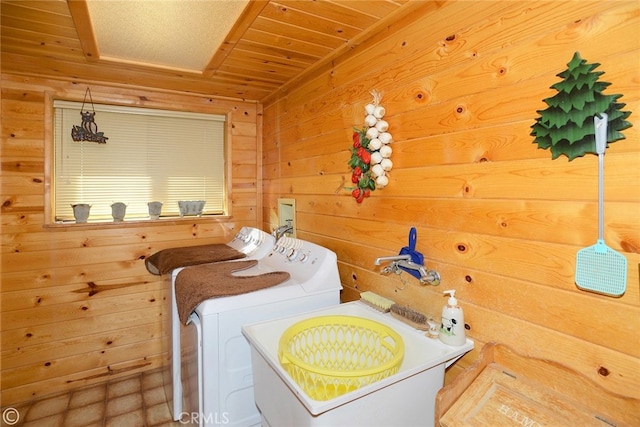 clothes washing area featuring sink, wooden walls, wood ceiling, and washing machine and clothes dryer