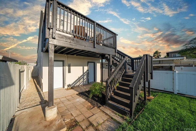 back house at dusk with a yard, a patio, and a deck