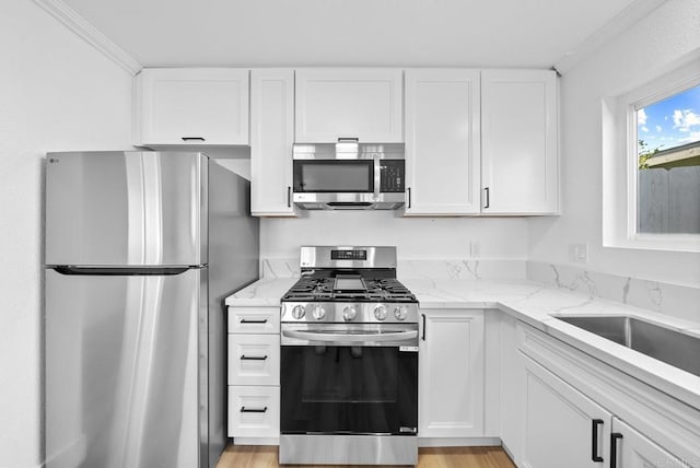 kitchen featuring appliances with stainless steel finishes, white cabinetry, and crown molding