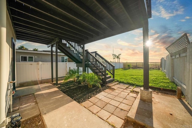 patio terrace at dusk featuring a lawn