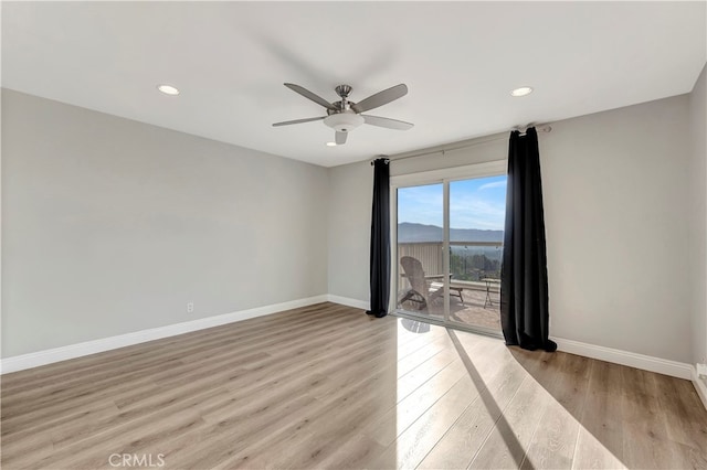 spare room with light hardwood / wood-style flooring, a mountain view, and ceiling fan