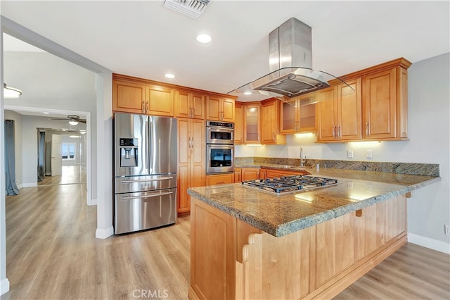 kitchen with island exhaust hood, kitchen peninsula, stainless steel appliances, light wood-type flooring, and light stone counters