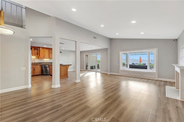 unfurnished living room with sink, hardwood / wood-style flooring, and high vaulted ceiling