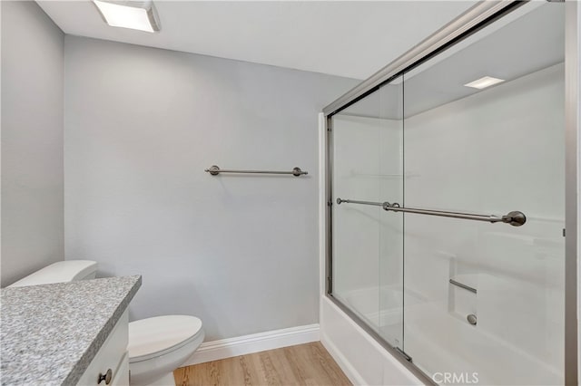 full bathroom featuring vanity, combined bath / shower with glass door, hardwood / wood-style flooring, and toilet