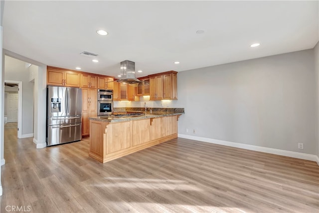 kitchen with island range hood, kitchen peninsula, a kitchen bar, light wood-type flooring, and appliances with stainless steel finishes