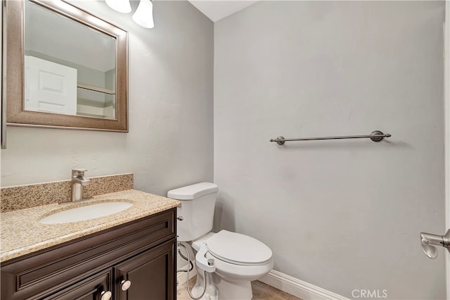 bathroom with toilet, vanity, and wood-type flooring