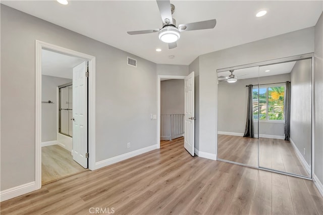 unfurnished bedroom with a closet, light hardwood / wood-style floors, ensuite bath, and ceiling fan