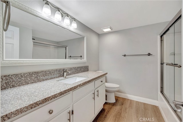 full bathroom featuring vanity, hardwood / wood-style flooring, toilet, and shower / bath combination with glass door