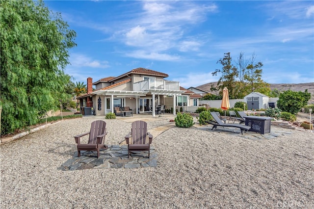 rear view of house with a patio, cooling unit, a fire pit, and a shed