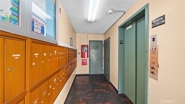 hall with elevator, mail boxes, and a textured ceiling