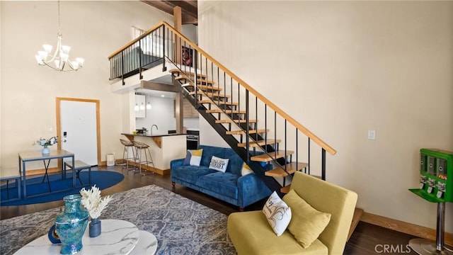 living room with a notable chandelier, dark hardwood / wood-style floors, beam ceiling, and a high ceiling