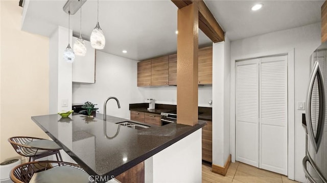 kitchen with stainless steel refrigerator with ice dispenser, kitchen peninsula, sink, and hanging light fixtures