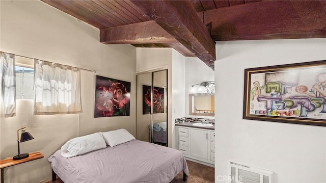 bedroom featuring wooden ceiling, sink, vaulted ceiling with beams, connected bathroom, and a closet