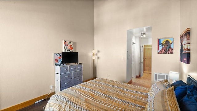 bedroom featuring ensuite bath, hardwood / wood-style floors, and a high ceiling