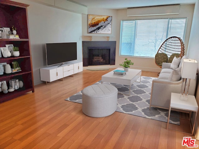 living room with a wall unit AC and light wood-type flooring