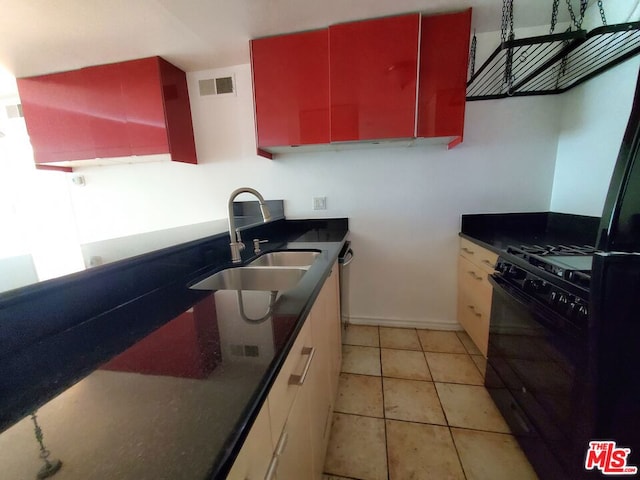 kitchen featuring sink, light tile patterned floors, and black gas range