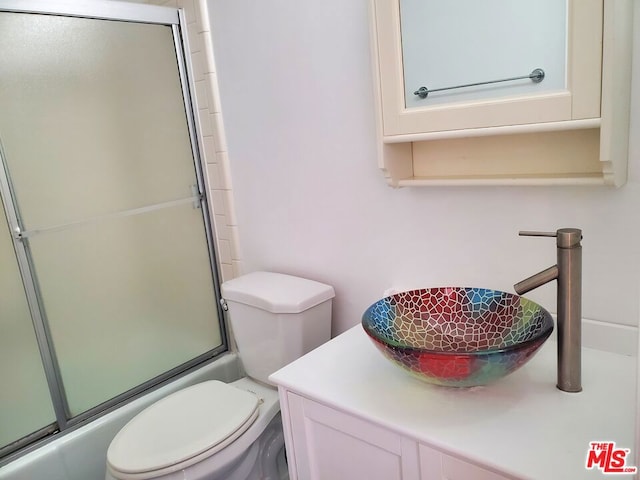 full bathroom featuring vanity, toilet, and bath / shower combo with glass door