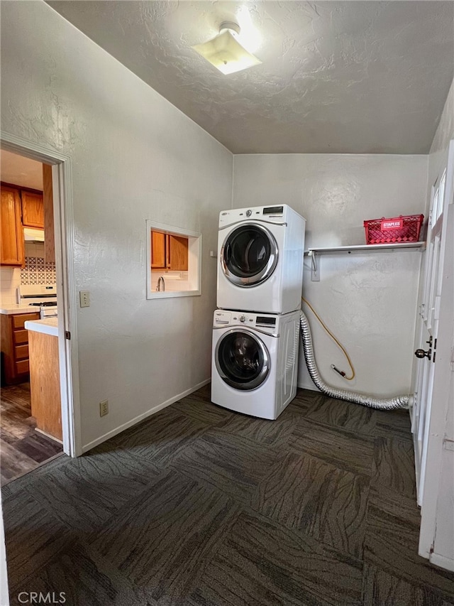 laundry room featuring a textured ceiling, stacked washer / dryer, and dark wood-type flooring