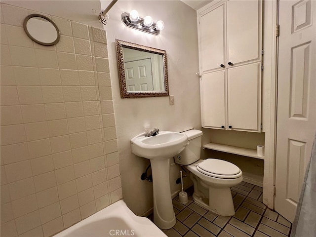 bathroom with tiled shower / bath, toilet, and tile patterned flooring