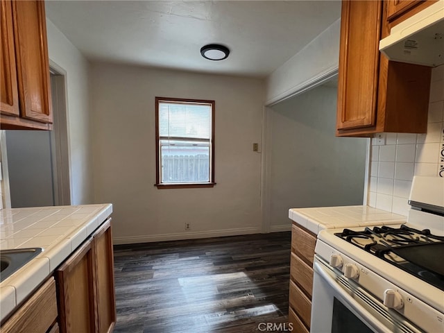 kitchen featuring white gas range oven, tasteful backsplash, tile counters, and dark hardwood / wood-style flooring