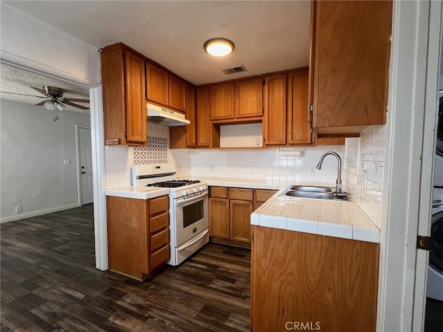 kitchen with decorative backsplash, dark hardwood / wood-style floors, white gas range oven, sink, and ceiling fan