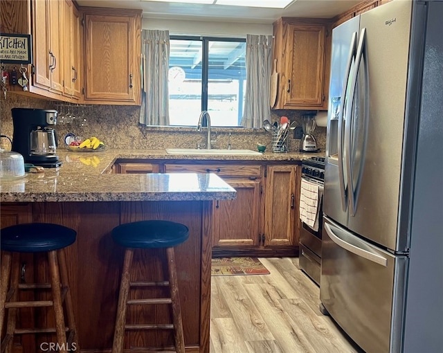 kitchen with a breakfast bar, kitchen peninsula, stainless steel appliances, and light wood-type flooring