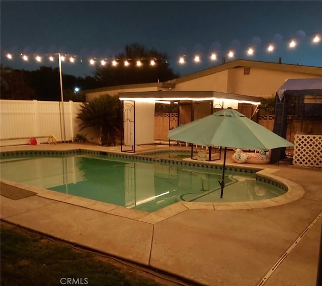 pool at twilight featuring a patio and a gazebo