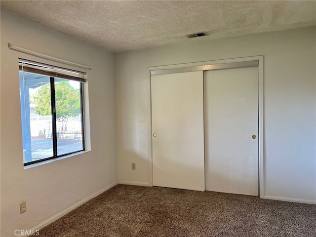 unfurnished bedroom featuring a closet, a textured ceiling, and carpet flooring