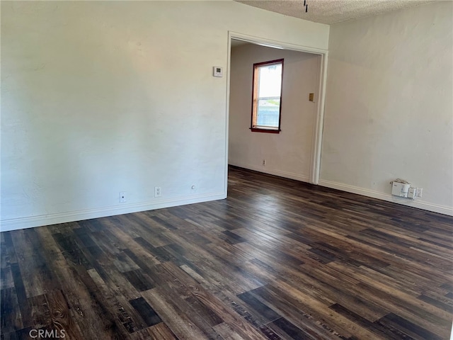 unfurnished room with a textured ceiling and dark hardwood / wood-style floors