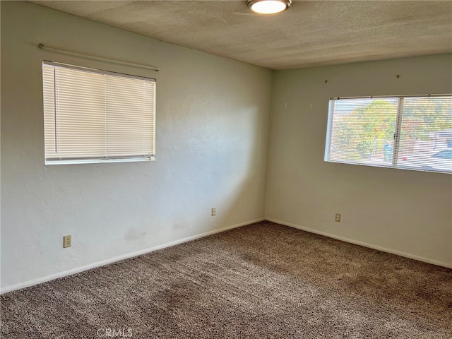 carpeted empty room featuring a textured ceiling