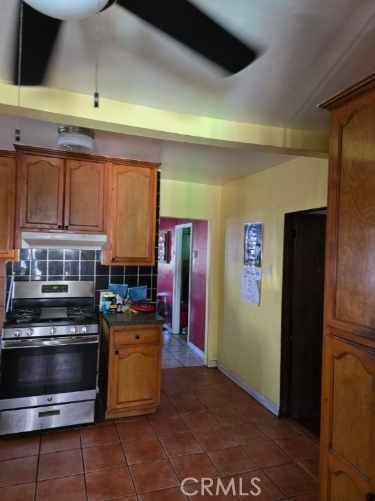 kitchen featuring dark tile patterned floors, stainless steel range, and tasteful backsplash