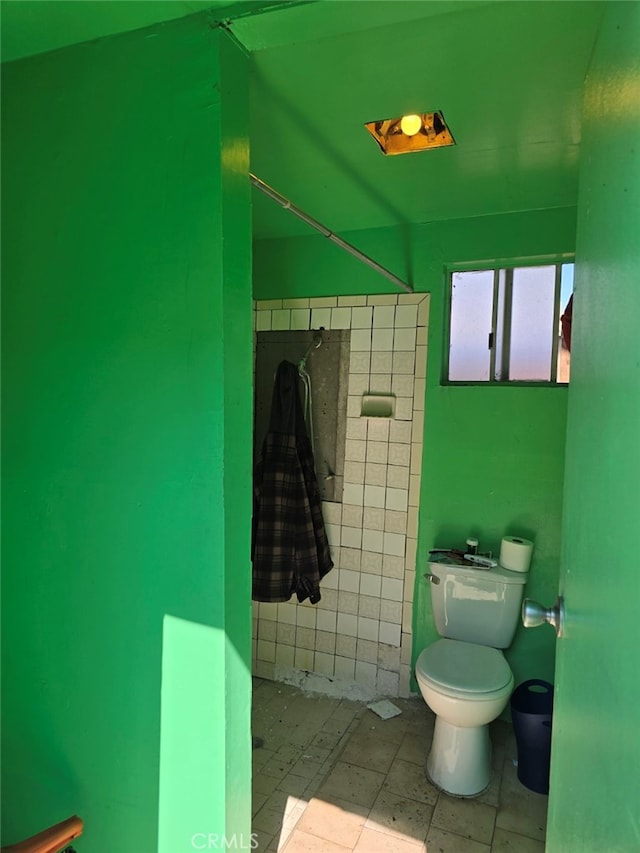 bathroom featuring toilet and tile walls