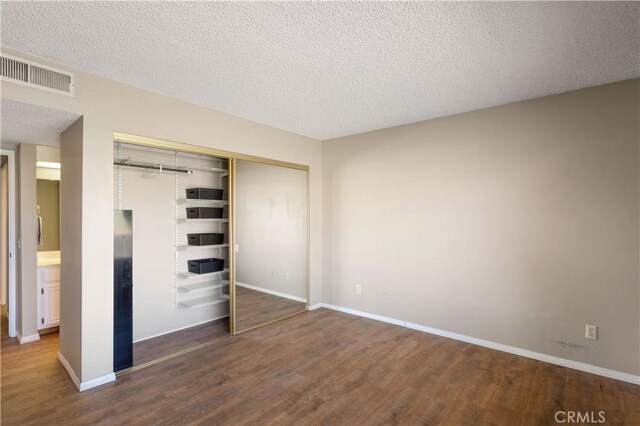 unfurnished bedroom with a closet, hardwood / wood-style floors, and a textured ceiling