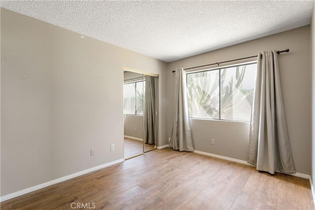 spare room featuring light hardwood / wood-style floors and a textured ceiling