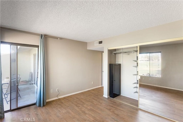 unfurnished bedroom with a closet, wood-type flooring, and a textured ceiling