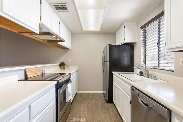 kitchen with white cabinetry, sink, stainless steel appliances, and hardwood / wood-style flooring