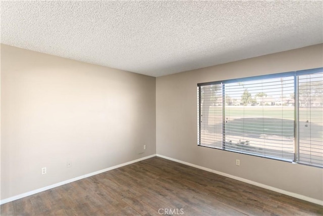 empty room with dark hardwood / wood-style flooring and a textured ceiling