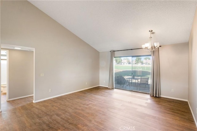 spare room with hardwood / wood-style floors, lofted ceiling, a textured ceiling, and a chandelier