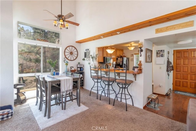 dining room featuring ceiling fan, light wood-type flooring, and a high ceiling