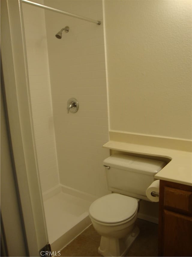 bathroom featuring vanity, tiled shower, and toilet