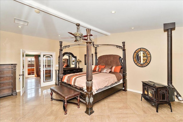 bedroom featuring a wood stove, beam ceiling, and ceiling fan