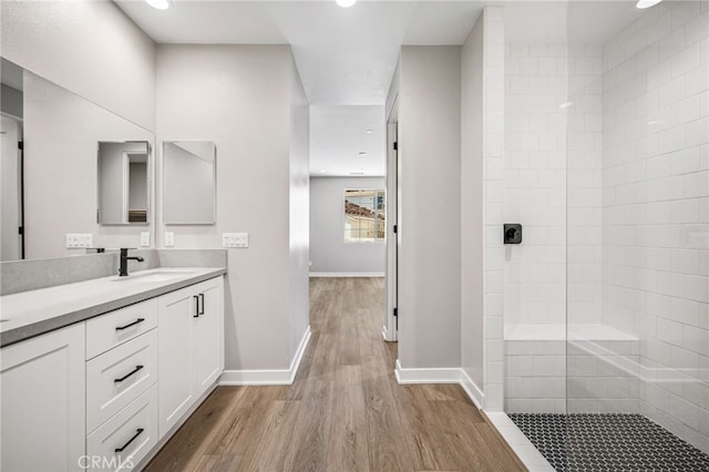 bathroom featuring a tile shower, vanity, and wood-type flooring